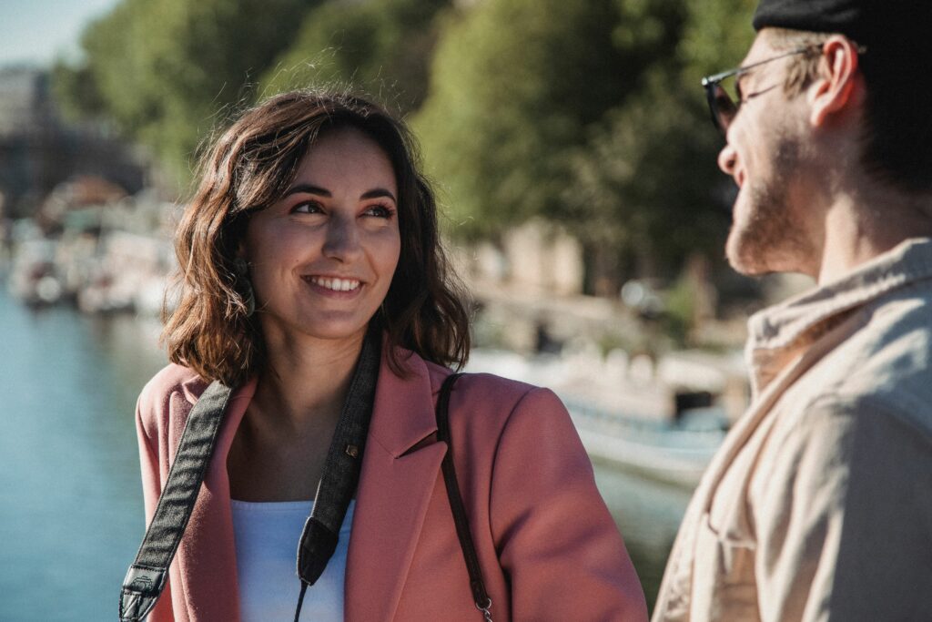 Femme souriante face à un homme, lors d'un date, en ballade dans Paris.